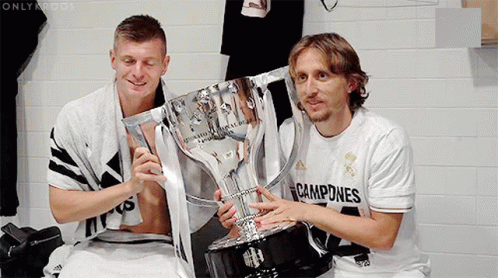 Two Soccer Players Holding A Trophy With The Word Campeones On Their Shirt GIF