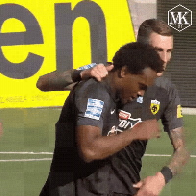 Two Soccer Players Hugging With MK Logo
