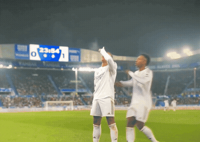 Two Soccer Players On A Field With A Scoreboard In The Background That Says 23:58 GIF