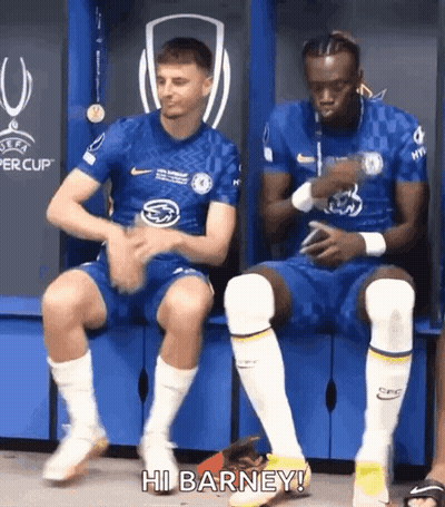 Two Soccer Players Sitting On Locker Room Bench One Talking GIF