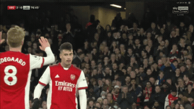 Two Soccer Players Wearing Emirates Fly Better Jerseys Are Standing In Front Of A Crowd GIF