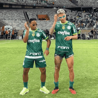 Two Soccer Players Wearing Green Crefisa Jerseys Are Dancing On A Field GIF