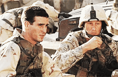 Two Soldiers Are Sitting Next To Each Other And One Is Wearing A Helmet That Says ' Us Marines ' On It GIF