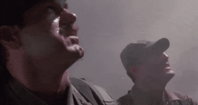 Two Soldiers Are Standing Next To Each Other In A Dark Room Looking Up At The Sky . GIF