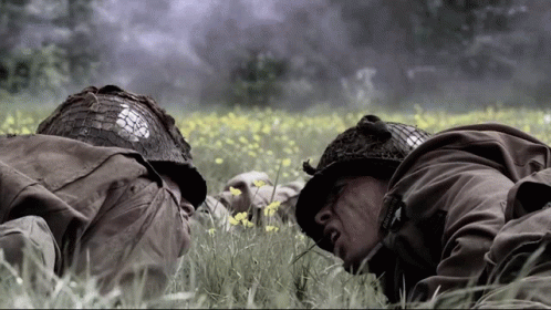 Two Soldiers Laying In A Field With One Wearing A Helmet That Says Us Army GIF