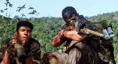 Two Soldiers One Of Whom Is Holding A Sniper Rifle With The Letter R On It GIF