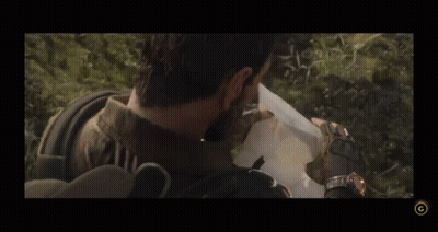 Two Soldiers Standing In The Woods With A G On The Bottom Right GIF