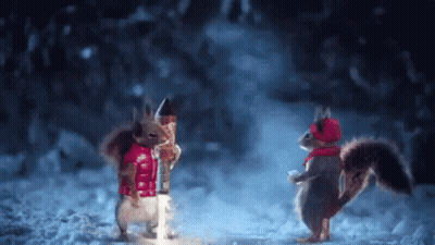 Two Squirrels Standing In Snow In Christmas Clothes GIF