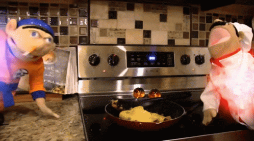 Two Stuffed Animals Cooking On Stove One In Chef Outfit GIF