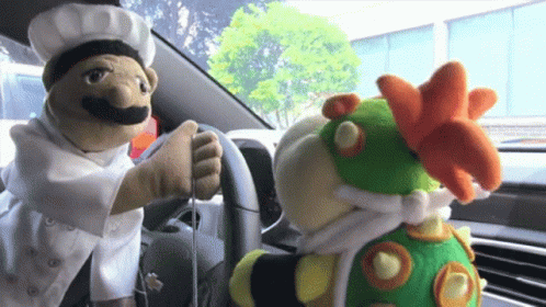 Two Stuffed Animals In Car One Chef One Bowser GIF