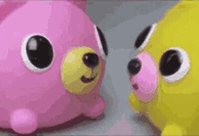 Two Stuffed Animals , One Pink And One Yellow , Are Standing Next To Each Other . GIF