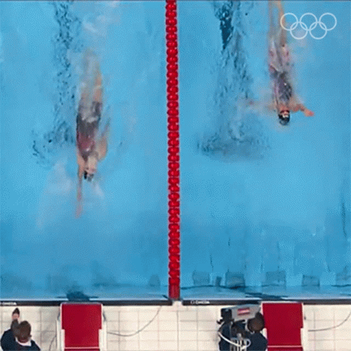 Two Swimmers Are Swimming In A Pool With The Olympic Rings On The Bottom GIF