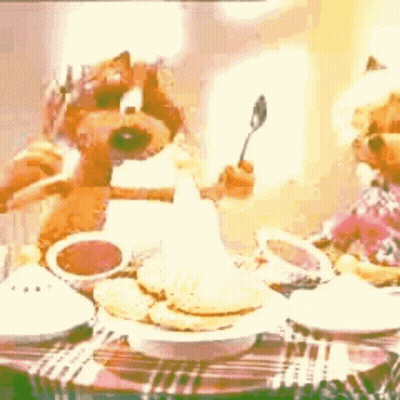 Two Teddy Bears Sitting At Table With Food And Spoon GIF