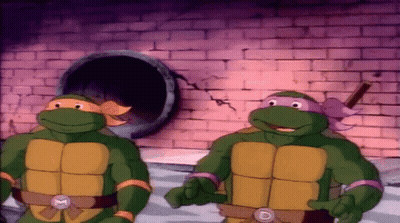 Two Teenage Mutant Ninja Turtles Are Standing Next To Each Other In Front Of A Brick Wall GIF