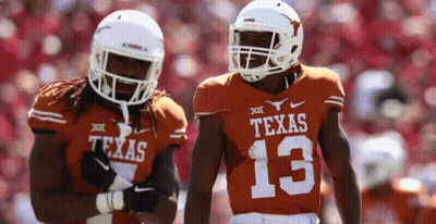 Two Texas Football Players Wearing Orange Uniforms Are Standing Next To Each Other GIF