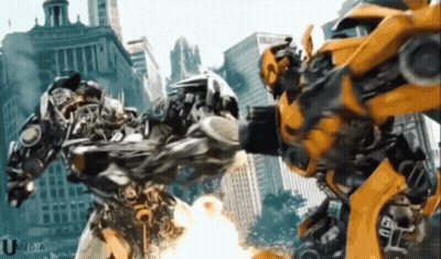 Two Transformers Fighting In Front Of City With Umedia GIF