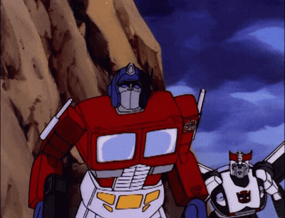 Two Transformers With Optimus Prime Text On Chest GIF