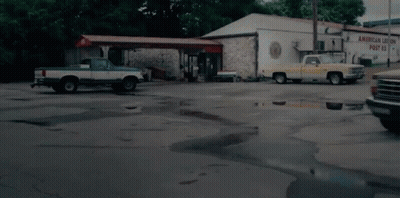 Two Trucks Parked In Front Of Building Saying American Union Post GIF