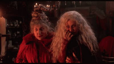 Two Witches Are Standing Next To Each Other And The Word Sorry Is On The Screen Behind Them GIF
