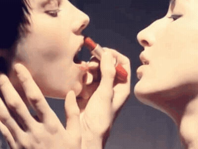 Two Women Applying Red Lipstick To Each Other GIF