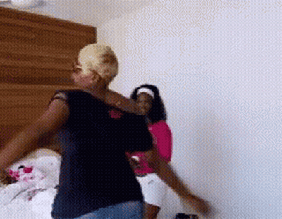 Two Women Are Dancing In A Room With A Wooden Headboard In The Background . GIF