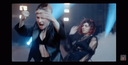 Two Women Are Dancing In Front Of A Blue Light . GIF