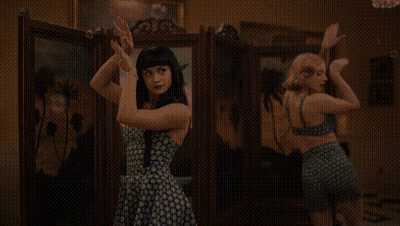Two Women Are Dancing In Front Of A Mirror In A Room . GIF
