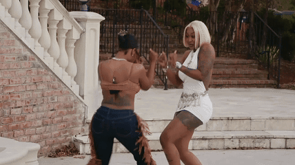Two Women Are Dancing In Front Of A Staircase GIF