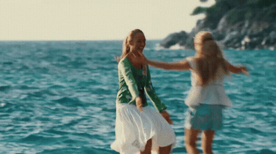 Two Women Are Dancing In The Ocean And Hugging Each Other GIF