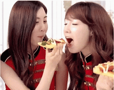 Two Women Are Eating Pizza Together And One Is Holding A Slice Of Pizza In Her Hand GIF