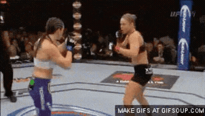 Two Women Are Fighting In A Boxing Ring In Front Of A Crowd Of People . GIF