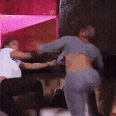 Two Women Are Fighting In A Room With Pink Lights GIF