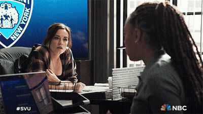 Two Women Are Having A Conversation In Front Of A New York Police Badge GIF