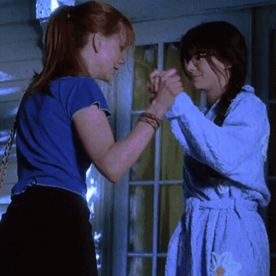 Two Women Are Holding Hands In Front Of A Glass Door GIF