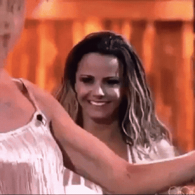 Two Women Are Hugging Each Other And Smiling In Front Of A Fire . GIF