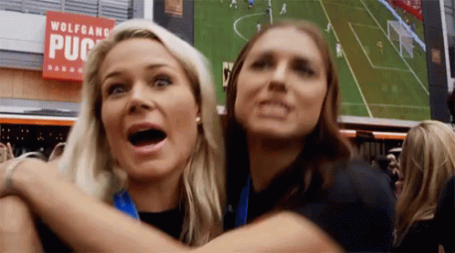 Two Women Are Hugging Each Other In Front Of A Sign That Says Wolfgang Pub GIF