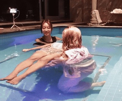 Two Women Are In A Swimming Pool And One Of Them Is Wearing A Pink Hoodie GIF