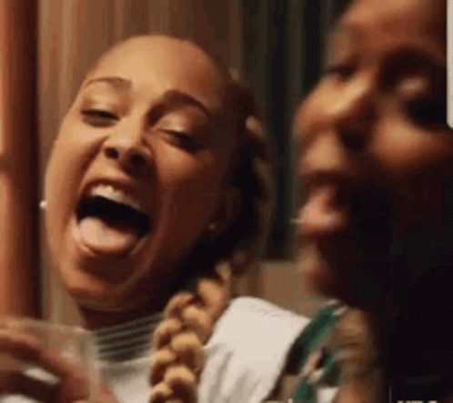 Two Women Are Laughing With Their Tongues Out And One Is Holding A Glass Of Wine . GIF