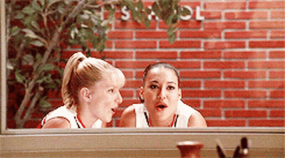 Two Women Are Looking Out Of A Window With A Brick Wall In The Background GIF