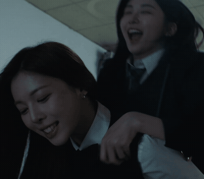 two women are playing with each other in a dark room and one is smiling