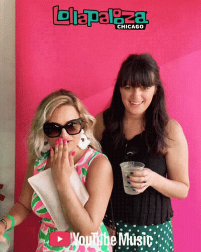 Two Women Are Posing For A Photo In Front Of A Pink Background That Says Lollapaloza Chicago GIF