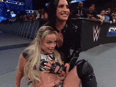 Two Women Are Posing For A Picture In Front Of A Wrestling Ring With The Letter W On It GIF