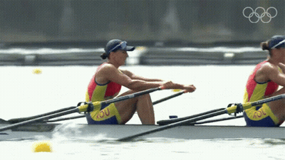Two Women Are Rowing In A Boat With Rou On Their Pants GIF