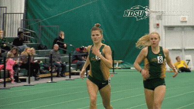 Two Women Are Running On A Track With Ndsu Written On The Wall Behind Them GIF