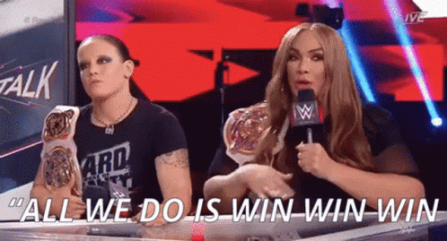 Two Women Are Sitting At A Table And One Of Them Is Holding A Microphone And Saying " All We Do Is Win Win Win " GIF