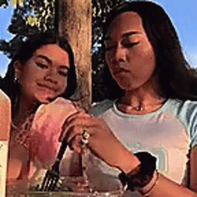 Two Women Are Sitting At A Table Eating Food . GIF