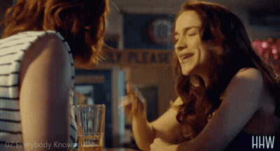 Two Women Are Sitting At A Table In Front Of A Sign That Says " Please " GIF