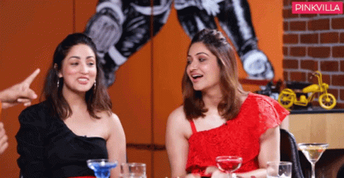 Two Women Are Sitting At A Table With Drinks And A Pinkvilla Logo Behind Them GIF