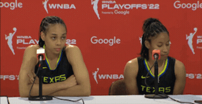 Two Women Are Sitting At A Table With Microphones In Front Of A Google Banner GIF