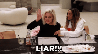 Two Women Are Sitting At A Table With The Word Liar Written On It GIF